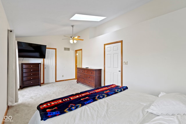 bedroom featuring lofted ceiling with skylight, ceiling fan, and light colored carpet