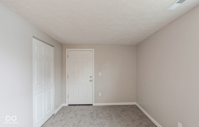 carpeted spare room with a textured ceiling