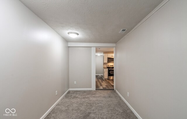 corridor with a textured ceiling and carpet floors