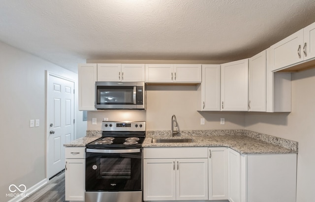 kitchen featuring white cabinets, appliances with stainless steel finishes, hardwood / wood-style floors, and sink