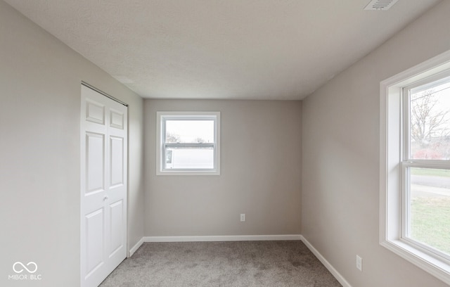 unfurnished bedroom featuring carpet floors, a textured ceiling, and a closet