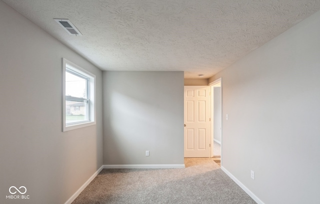 empty room with carpet and a textured ceiling