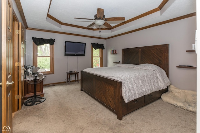 carpeted bedroom featuring ceiling fan, ornamental molding, and a tray ceiling