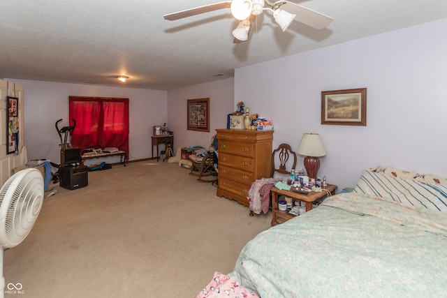 bedroom with ceiling fan, light colored carpet, and a textured ceiling