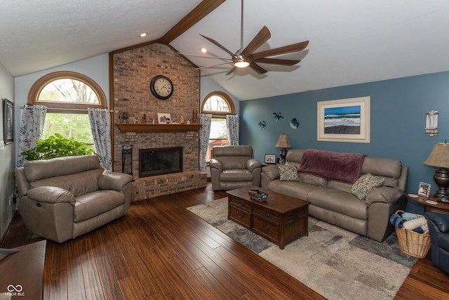 living room with vaulted ceiling with beams, dark hardwood / wood-style floors, ceiling fan, and a brick fireplace