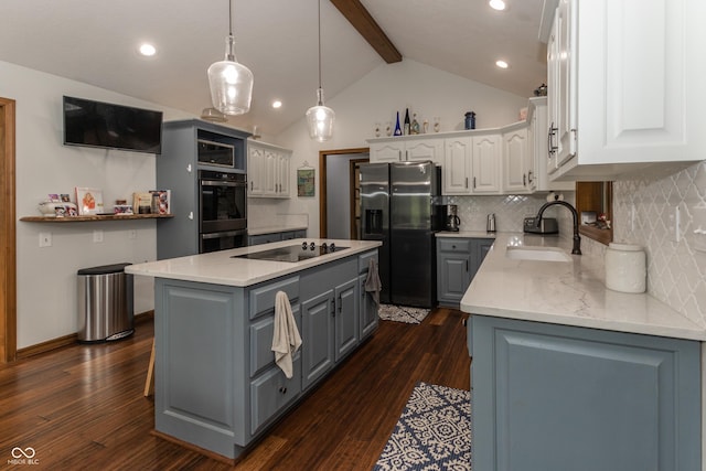 kitchen featuring dark wood-type flooring, sink, appliances with stainless steel finishes, a kitchen island, and white cabinetry