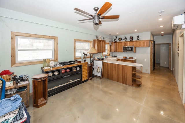 kitchen with kitchen peninsula, ceiling fan, sink, and a wall mounted air conditioner