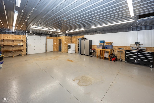 garage featuring a workshop area, washer / clothes dryer, and wood walls