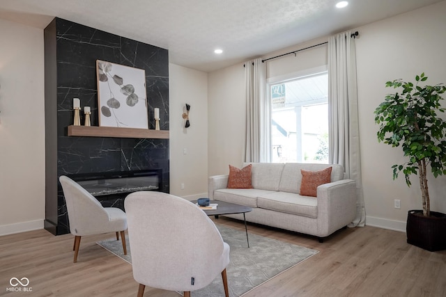 living room featuring a premium fireplace, light hardwood / wood-style floors, and a textured ceiling