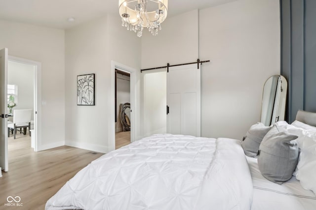 560 Jefferson Ave, Indianapolis, IN 46201 - bedroom featuring light wood-type flooring, baseboards, a chandelier, a barn door, and a towering ceiling