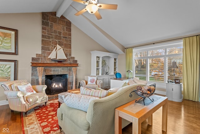 living room with hardwood / wood-style flooring, vaulted ceiling with beams, ceiling fan, and a stone fireplace