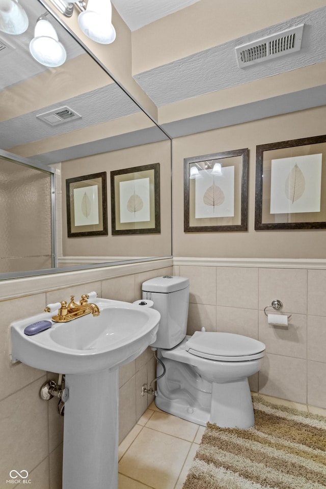 bathroom with tile patterned floors, tile walls, and toilet