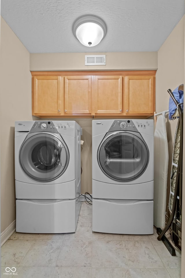 clothes washing area featuring cabinets, independent washer and dryer, and a textured ceiling