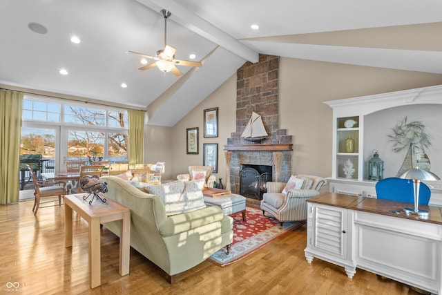 living room with ceiling fan, beam ceiling, high vaulted ceiling, light hardwood / wood-style flooring, and a fireplace