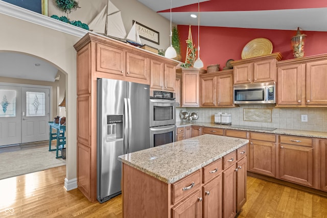 kitchen with decorative backsplash, appliances with stainless steel finishes, light wood-type flooring, and vaulted ceiling