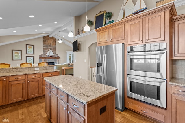 kitchen with vaulted ceiling with beams, decorative light fixtures, light wood-type flooring, and stainless steel appliances