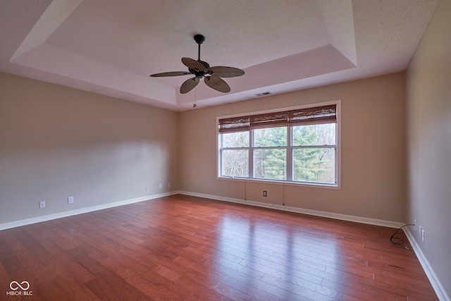 spare room with a tray ceiling, ceiling fan, and hardwood / wood-style floors