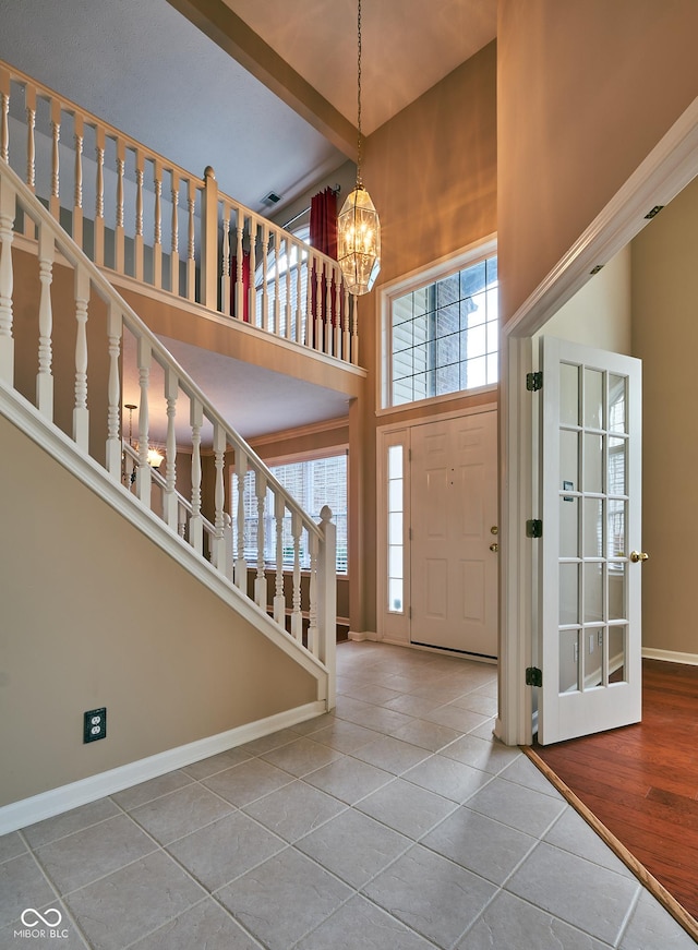 entrance foyer with tile patterned floors, a high ceiling, and a chandelier