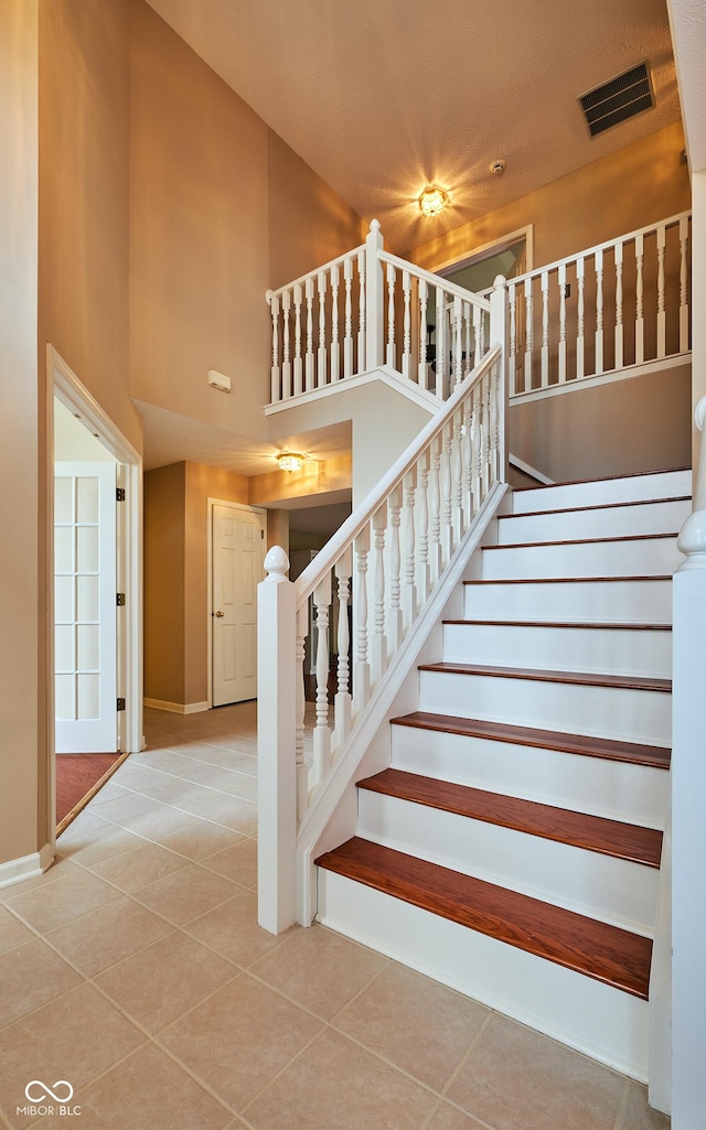 stairway featuring tile patterned flooring and a high ceiling