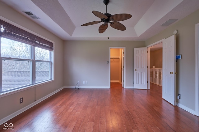 spare room with hardwood / wood-style floors, a raised ceiling, and ceiling fan