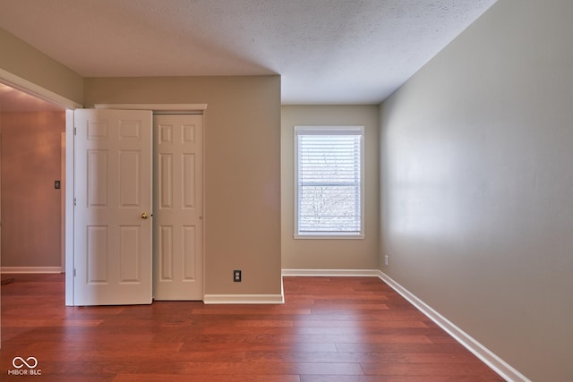 unfurnished bedroom featuring a textured ceiling, a closet, and dark hardwood / wood-style floors