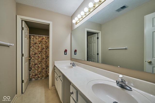 bathroom featuring a textured ceiling, vanity, and tile patterned floors