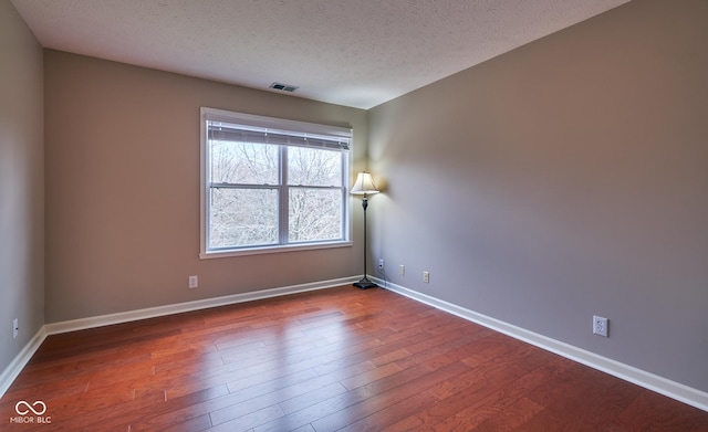 empty room featuring wood-type flooring and a textured ceiling