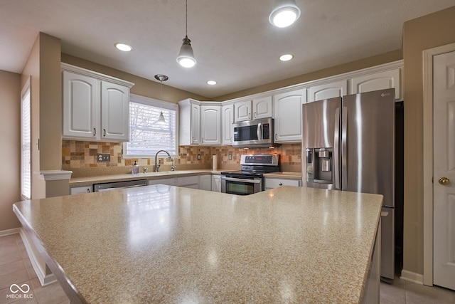 kitchen with decorative backsplash, appliances with stainless steel finishes, sink, pendant lighting, and white cabinetry