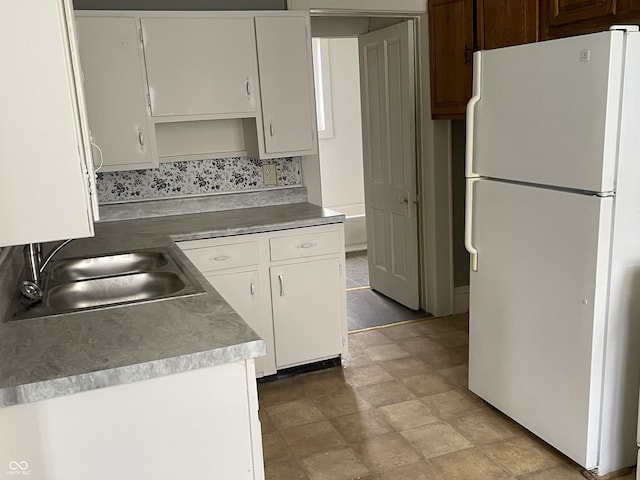 kitchen featuring white cabinets, white refrigerator, and sink