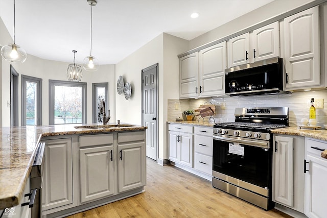 kitchen featuring light hardwood / wood-style floors, light stone counters, hanging light fixtures, and appliances with stainless steel finishes