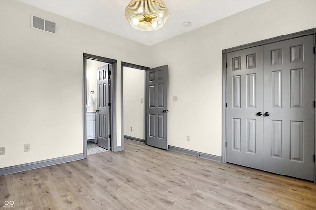 unfurnished bedroom with ensuite bath, light hardwood / wood-style flooring, and a closet