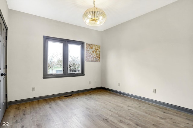 unfurnished room with light hardwood / wood-style flooring and an inviting chandelier