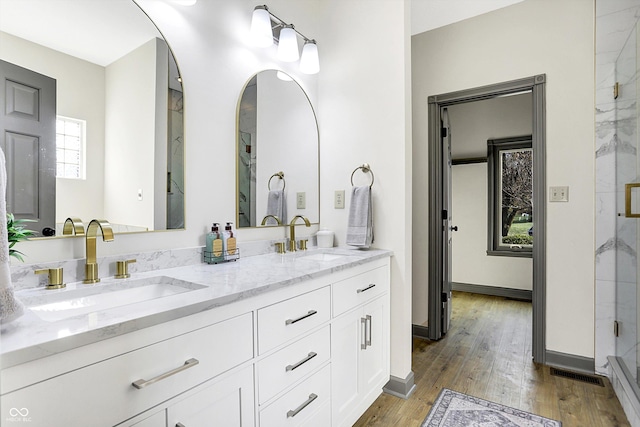 bathroom with hardwood / wood-style flooring, vanity, and a shower with shower door