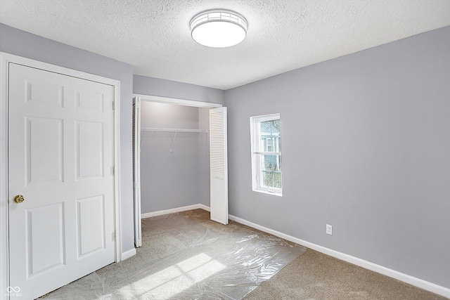 unfurnished bedroom featuring a textured ceiling, light colored carpet, and a closet