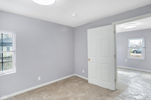 spare room featuring a textured ceiling and light carpet