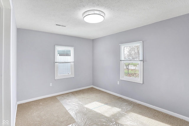 carpeted spare room featuring a textured ceiling