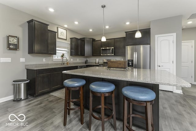 kitchen with dark wood-type flooring, a kitchen island, hanging light fixtures, and appliances with stainless steel finishes