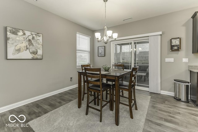 dining room with dark hardwood / wood-style floors and an inviting chandelier