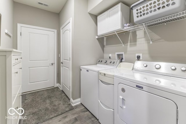 laundry area with cabinets, independent washer and dryer, and dark hardwood / wood-style flooring