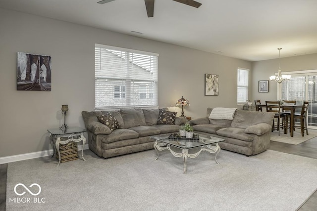 carpeted living room with ceiling fan with notable chandelier