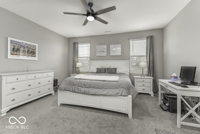 bedroom with multiple windows, ceiling fan, and light colored carpet