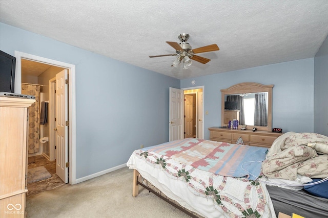 bedroom featuring connected bathroom, ceiling fan, light carpet, and a textured ceiling