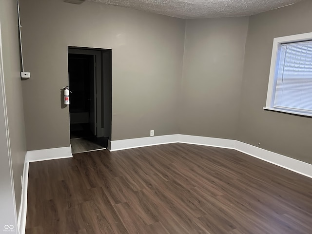 spare room featuring dark hardwood / wood-style floors and a textured ceiling