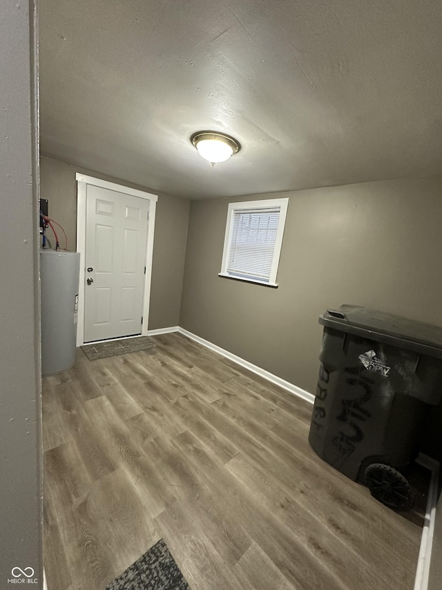 interior space with wood-type flooring, electric water heater, and a textured ceiling