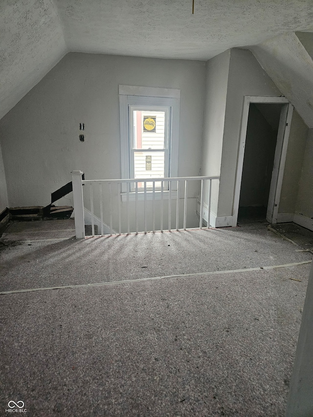 bonus room featuring a textured ceiling, carpet floors, and lofted ceiling