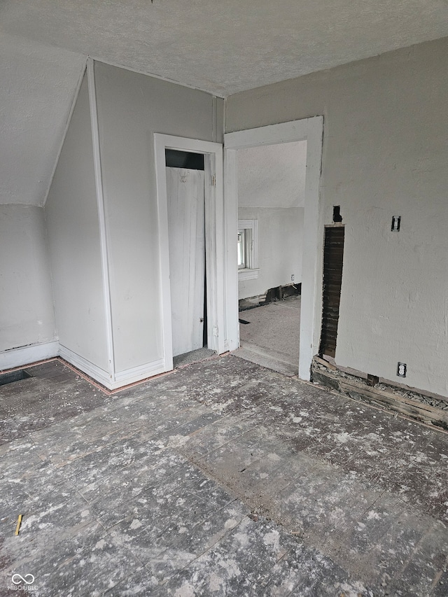 interior space with a textured ceiling and vaulted ceiling