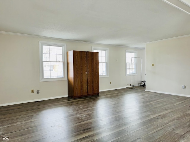 spare room with crown molding, a healthy amount of sunlight, and dark hardwood / wood-style floors