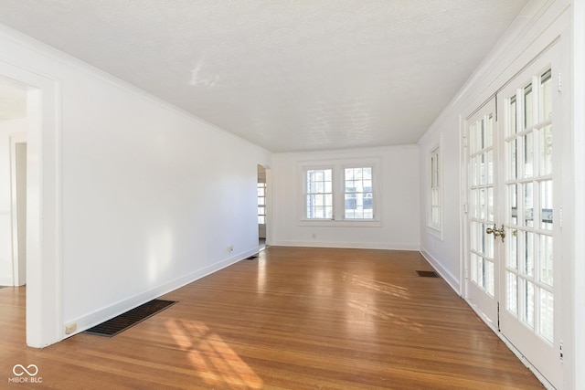 unfurnished room with french doors, hardwood / wood-style floors, a textured ceiling, and ornamental molding