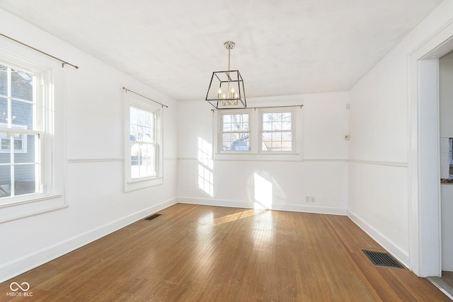 unfurnished dining area with a chandelier and hardwood / wood-style flooring