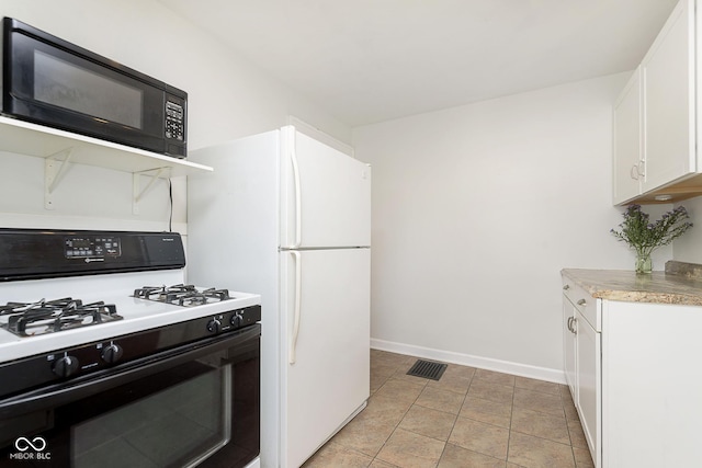 kitchen with white gas range, white cabinets, and light tile patterned floors